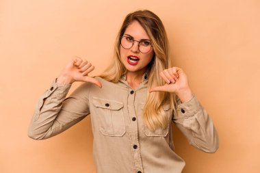 Bej arka planda izole edilmiş genç beyaz kadın gururlu ve kendinden emin hissediyor, örnek olarak.