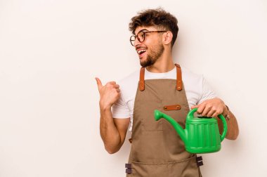 Genç bahçıvan İspanyol bir su bidonu tutuyor beyaz arka planda parmak uzakta, gülen ve kaygısız..