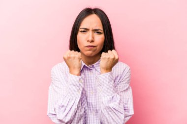 Pembe arka planda izole edilmiş genç İspanyol kadın kameraya yumruğunu, agresif yüz ifadesini gösteriyor..