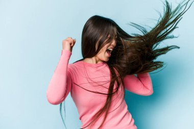 Genç Asyalı kadın mavi arka planda saç taşıyor.