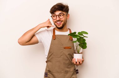 Genç bahçıvan İspanyol bir bitki tutuyor. Beyaz arka planda izole edilmiş. Cep telefonu hareketini parmaklarıyla gösteriyor..