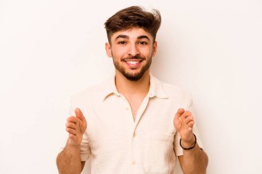 Beyaz arka planda izole edilmiş genç İspanyol adam iki eliyle bir şey tutuyor, ürün sunumu..