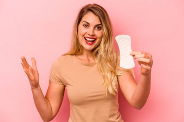 Pembe arka planda izole edilmiş hijyenik peçete tutan beyaz bir kadın hoş bir sürprizle karşılaşıyor, heyecanlı ve el kaldırıyor..
