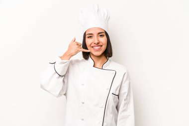 Beyaz arka planda izole edilmiş genç İspanyol aşçı kadın parmaklarıyla bir cep telefonu hareketi gösteriyor..