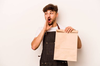 Beyaz arka planda izole edilmiş bir paket taşıyan genç İspanyol tezgahtar gizli bir sıcak fren haberinden bahsediyor ve yana bakıyor.