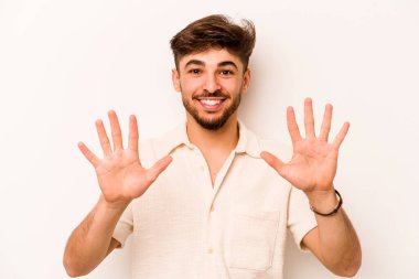 Beyaz arka planda izole edilmiş genç İspanyol adam on numarayı elleriyle gösteriyor..