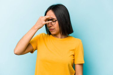 Genç İspanyol kadın mavi arka planda izole edilmiş, başı ağrıyor, yüzüne dokunuyor..