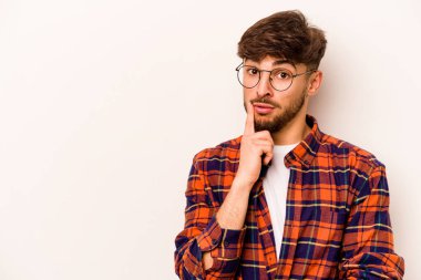 Beyaz arka planda izole edilmiş genç bir İspanyol şüpheli ve şüpheci bir ifadeyle yana bakıyor..