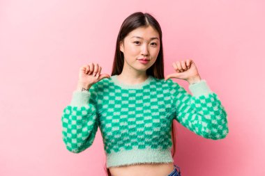 Pembe arka planda izole edilmiş genç Çinli kadın gururlu ve kendinden emin hissediyor, örnek olarak..