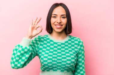 Pembe arka planda izole edilmiş genç İspanyol kadın neşeli ve kendinden emin, iyi bir hareket gösteriyor..