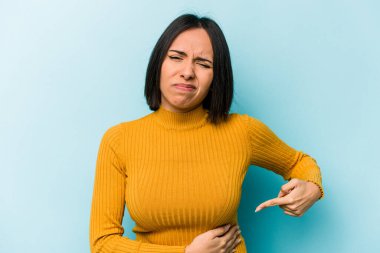 Mavi arka planda karaciğer ağrısı çeken, karnı ağrıyan genç bir İspanyol kadın..