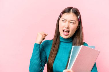 Pembe arka planda kitap tutan Asyalı genç bayan zafer kazandıktan sonra yumruğunu kaldırdı, kazanan kavram..