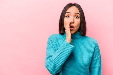 Pembe arka planda izole edilmiş genç İspanyol kadın gizli bir sıcak fren haberi veriyor ve yan bakıyor.