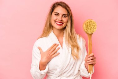 Pembe arka planda izole edilmiş sırt kaşıyıcı saklayan beyaz bir kadın kahkahalar atıyor..