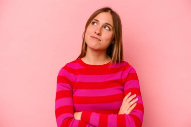 Pembe arka planda izole edilmiş genç beyaz kadın hedeflere ve amaçlara ulaşma hayali kuruyor.