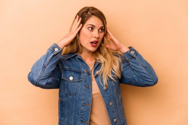 Beyaz tenli genç bir kadın bej arka planda izole edilmiş bağırıyor, çok heyecanlı, tutkulu, bir şeyden memnun..