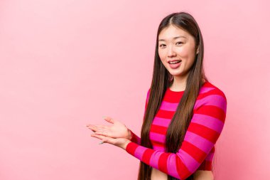 Pembe arka planda izole edilmiş genç Çinli bir kadın avucunun içinde bir kopya alanı tutuyor..