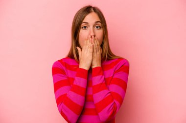 Pembe arka planda izole edilmiş beyaz bir kadın elleriyle ağzını kapatırken şok oldu..