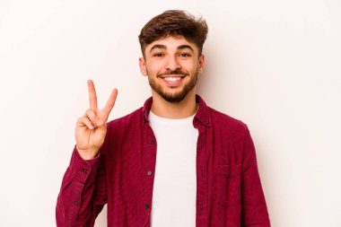 Beyaz arka planda izole edilmiş genç İspanyol adam iki numarayı parmaklarıyla gösteriyor..