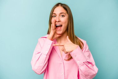 Kafkasyalı genç bir kadın mavi arka planda izole edilmiş. Dedikodu yapıyor, bir şeyleri bildiriyor..