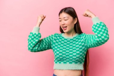 Pembe arka planda izole edilmiş genç Çinli bir kadın zaferden sonra yumruğunu kaldırıyor, kazanan konsept..