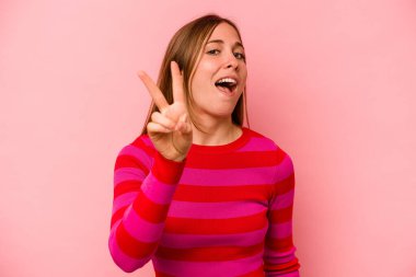 Pembe arka planda izole edilmiş genç beyaz kadın iki numarayı parmaklarıyla gösteriyor..