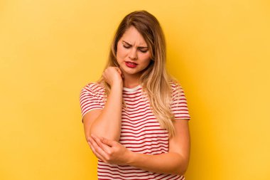 Beyaz bir kadın sarı arka planda izole edilmiş dirsek masajı yapıyor, kötü bir hareketin ardından acı çekiyor..