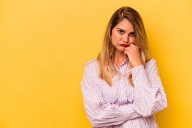 Sarı arka planda izole edilmiş, üzgün ve dalgın hisseden, kopyalama alanına bakan beyaz bir kadın..