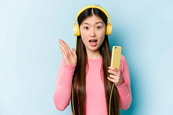 Jovem Mulher Asiática Ouvindo Música Isolada Fundo Azul Surpreso Chocado — Fotografia de Stock