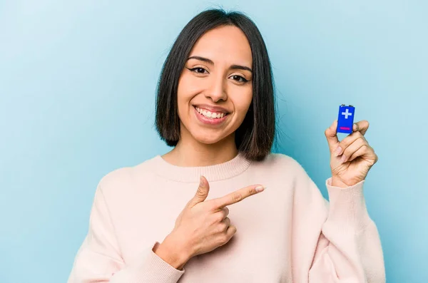 青い背景に電池を持っている若いヒスパニック系の女性は笑顔と脇を指して 空白のスペースで何かを示す — ストック写真