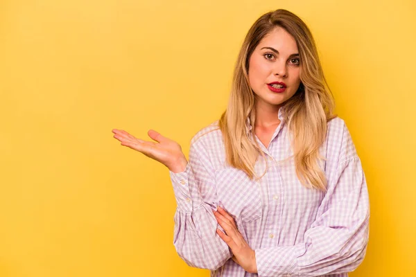 Jovem Caucasiana Isolado Fundo Amarelo Impressionado Segurando Espaço Cópia Palma — Fotografia de Stock