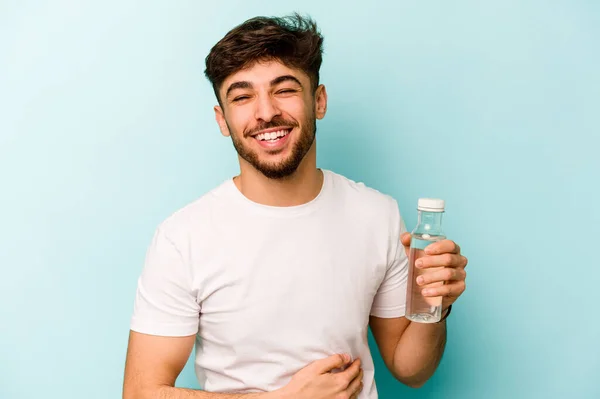 Pemuda Hispanik Memegang Botol Air Terisolasi Latar Belakang Putih Tertawa — Stok Foto