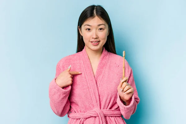 年轻的亚洲女人穿着浴衣刷牙 与粉红背景的人隔离 手指衬衫的复制品空间 自豪而自信 — 图库照片
