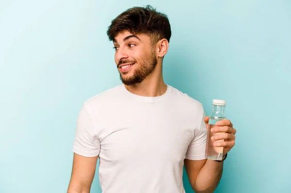 Νεαρός Ισπανός Κρατώντας Ένα Μπουκάλι Νερό Απομονωμένο Λευκό Φόντο Κοιτάζει — Φωτογραφία Αρχείου