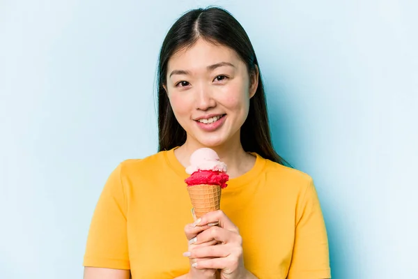 年轻的亚洲女人吃着蓝色背景的冰淇淋 — 图库照片