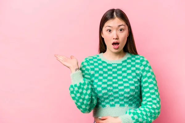 Joven Mujer China Aislada Sobre Fondo Rosa Impresionado Sosteniendo Espacio —  Fotos de Stock