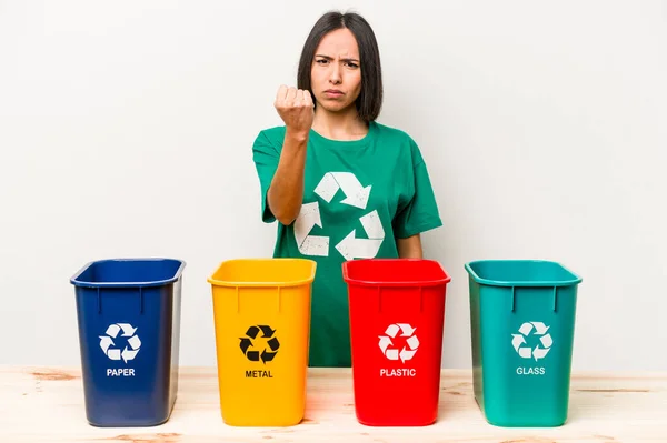 Young hispanic woman recycling isolated on white background showing fist to camera, aggressive facial expression.
