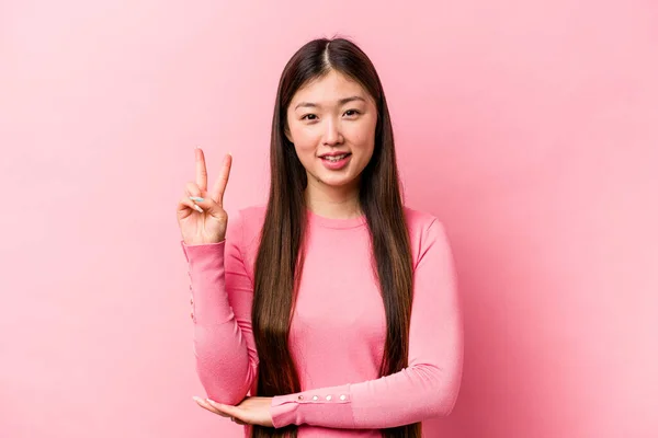 在粉色背景上被隔离的年轻中国女人用手指展示了二号 — 图库照片
