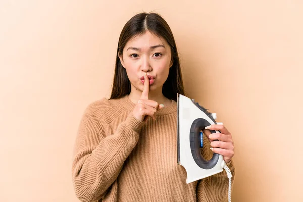 Ung Asiatisk Kvinna Håller Järn Isolerad Beige Bakgrund Hålla Hemlighet — Stockfoto