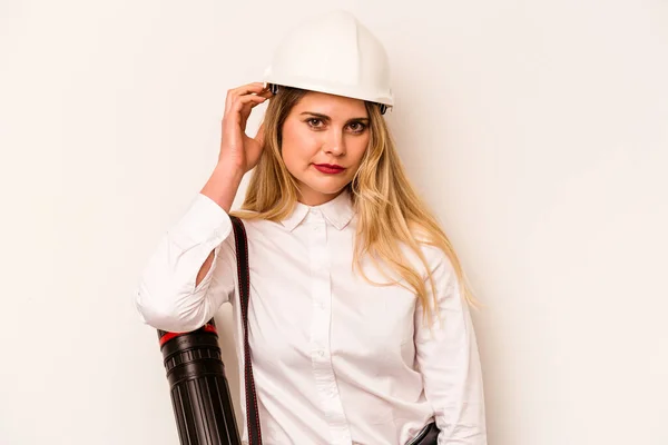 Young architect woman with helmet and holding blueprints isolated on white background being shocked, she has remembered important meeting.