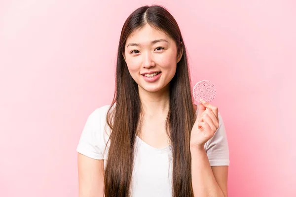 年轻的亚洲女人 手握粉红背景的面部海绵 — 图库照片