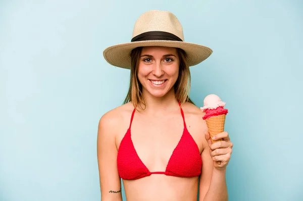 若いですCaucasian女性を身に着けていますビキニとホールドアイスクリーム隔離上の青の背景幸せな 笑顔と陽気な — ストック写真