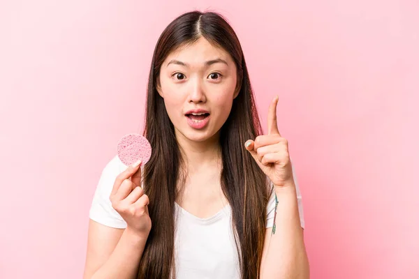 年轻的亚洲女人 手握粉红背景的面部海绵 有想法 有灵感 — 图库照片