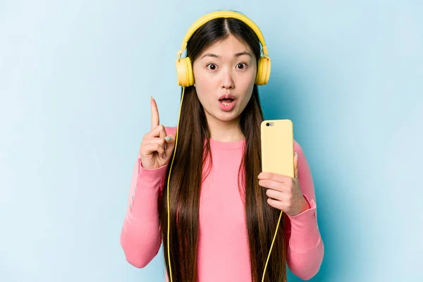 Jovem Mulher Asiática Ouvindo Música Isolada Fundo Azul Tendo Alguma — Fotografia de Stock