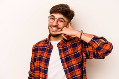 Beyaz arka planda izole edilmiş genç bir İspanyol, parmakları olan bir cep telefonu hareketi gösteriyor..