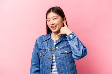 Pembe arka planda izole edilmiş genç Çinli bir kadın parmakları olan bir cep telefonu hareketi gösteriyor..