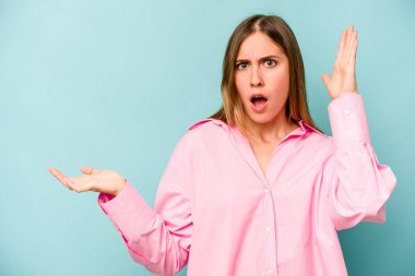 Mavi arka planda izole edilmiş beyaz bir kadın avuç içinde fotokopi alanı tutuyor, el üstünde tutuyor. Şaşırmış ve mutlu..