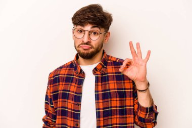 Beyaz arka planda izole edilmiş genç İspanyol bir adam bir göz kırptı ve elleriyle iyi bir jest yaptı..