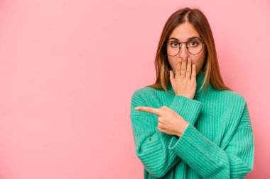 Pembe arka planda izole edilmiş genç beyaz kadın yan tarafı gösteriyor.