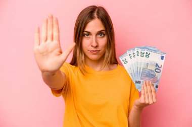 Pembe arka planda soyutlanmış banknotları tutan beyaz bir kadın elini uzatıp dur işaretini göstererek seni engelliyor..